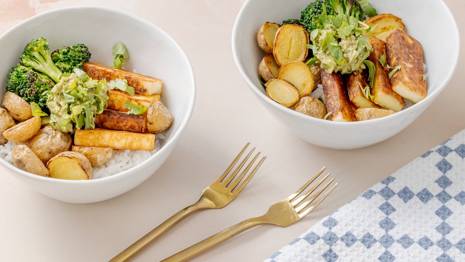 Two burrito bowls with grilled halloumi and Little Potatoes.