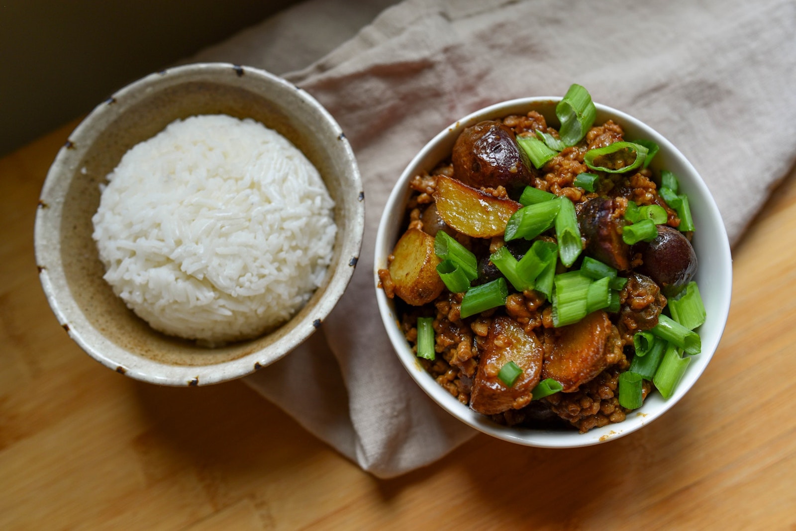 Two bowls next to eachother, one with rice and one with pork and Little Potatoes.