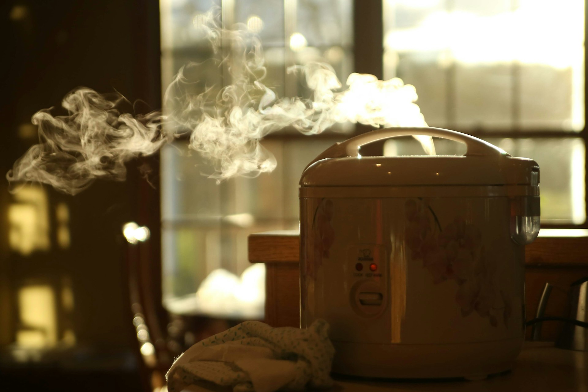 A slow cooker on a kitchen counter with steam rising out of the top.