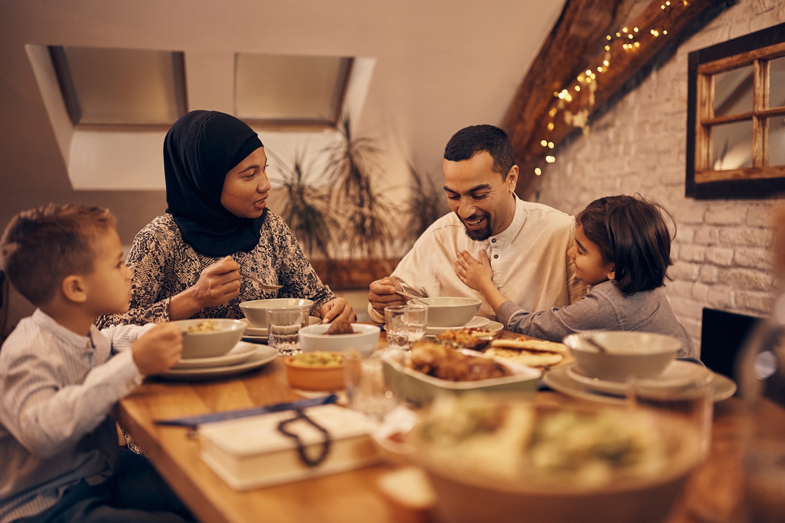 A family of four sits around a cozy dinner table and enjoys a meal together.